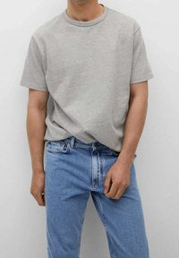 Camiseta de algodón gris con cuello redondo, combinada con jeans de mezclilla azul claro, con un ligero desgaste y un corte clásico de pierna recta.