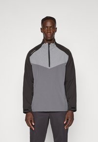 Grå strukturert halv-zip genser med svarte ermer, med et chevronmønster. Myk stoff med en jevn tekstur, inkluderer borrelåslukking.