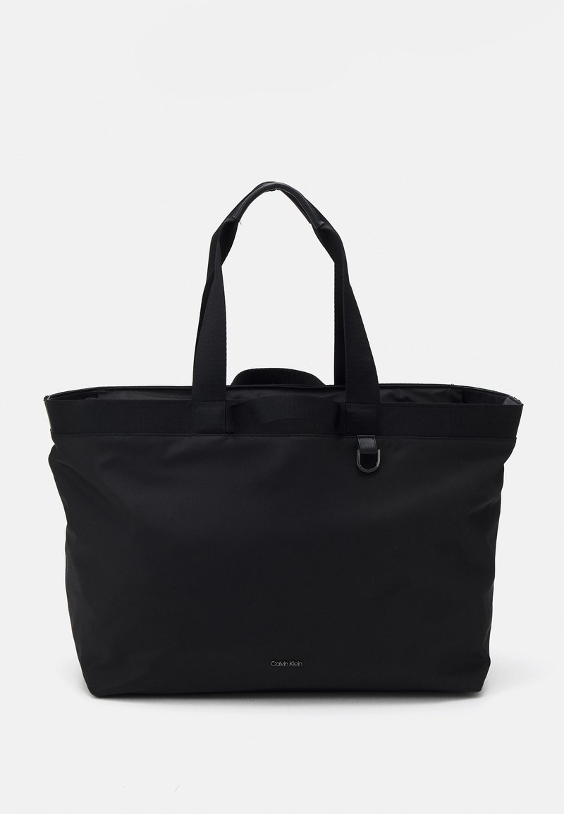 Svart tote-väskan med dubbla tyghandtag, dragkedjestängning och minimalistisk design. Har subtil varumärkesprofilering på framsidan. Hållbart material.
