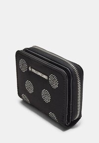 Portafoglio nero con pois argentati applicati, chiusura con zip e dettaglio del logo. Realizzato in materiale testurizzato, ha una forma rettangolare compatta.