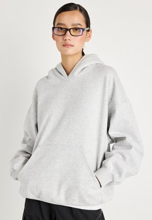 Lysegrå hoodie lavet af blødt stof, med en frontlomme og en stor hætte. Designet inkluderer ribbede manchetter og løs pasform.
