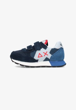 Scarpa da ginnastica blu navy e bianca con logo geometrico rosso, cinturini in velcro, tallone in suede blu e suola nera, vista laterale su sfondo bianco.