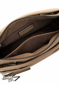 Interno di una borsa a tracolla in pelle beige con una foderatura in tessuto marrone, presenta un compartimento con zip e tasche aggiuntive per l'organizzazione.
