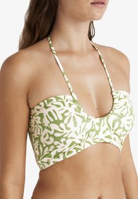 Bikini top s zeleno-bílým vzorem a řaseným designem, s tenkými ramínky a hlubokým výstřihem. Vyroben z elastického materiálu.