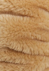 Tejido de piel sintética en un suave color marrón claro, con una textura estriada que presenta fibras gruesas y esponjosas, además de un ligero brillo.