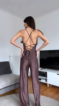 Combinaison bronze scintillante avec dos ouvert, design à bretelles croisées et détails à lacets. Jambes évasées s'étendant de la taille jusqu'au sol.