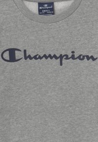 Felpa grigia in cotone con il logo "Champion" blu navy in evidenza sul petto. Girocollo con una texture morbida.