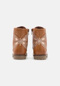 Bottines en cuir marron avec un motif de papillon scintillant décoratif de chaque côté et une fermeture éclair sur le côté pour un enfilage facile.