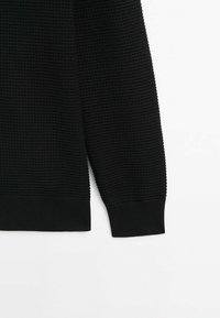 Pull en maille noir à manches longues avec poignets et ourlet côtelés, présentant un motif tissé horizontal texturé.