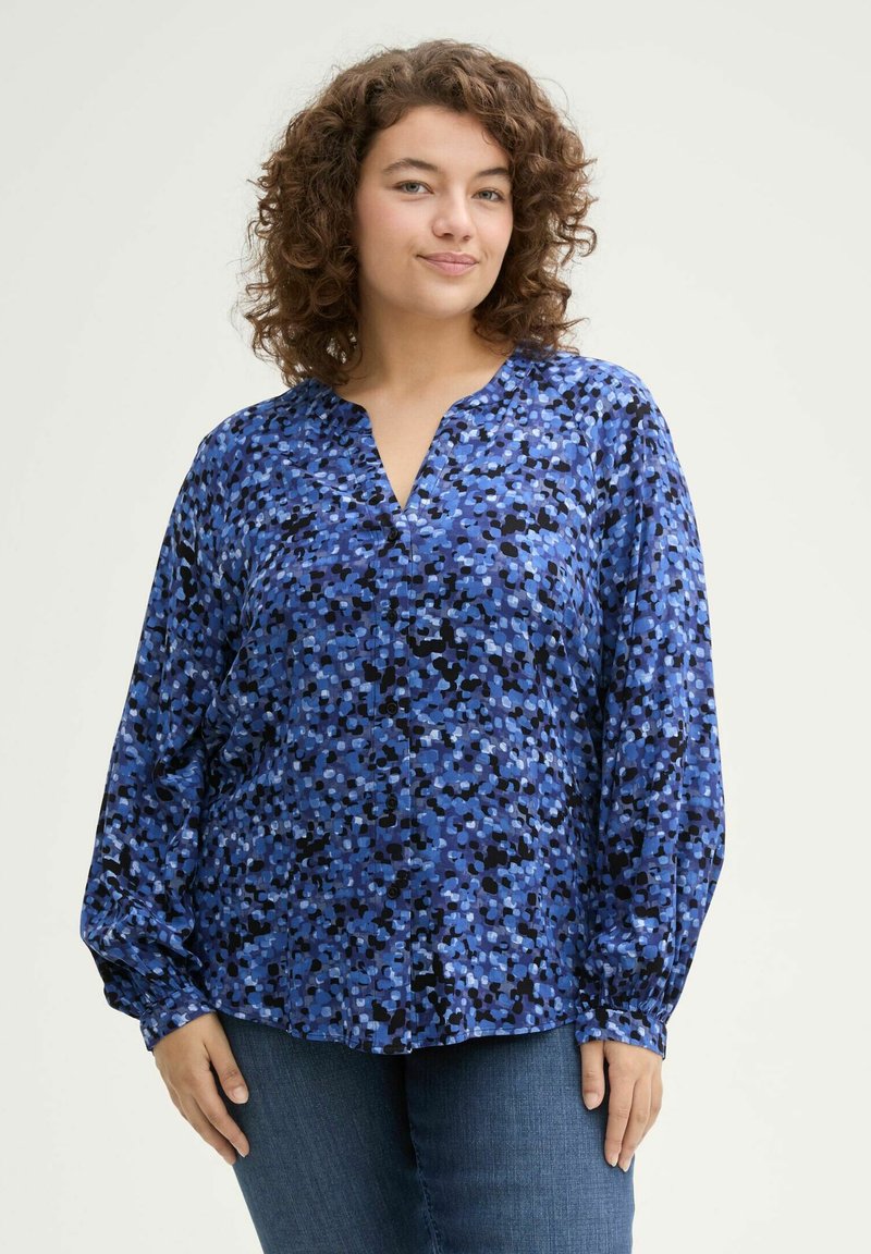 Blaue blusige Bluse mit V-Ausschnitt und langen Ärmeln, die eine Mischung aus kleinen blauen, schwarzen und helleren Farbtönen aufweist, mit Knopfdetails auf der Vorderseite.