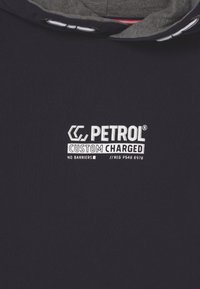 Marinblå sweatshirt med grå huva som har vit text "PETROL CUSTOM CHARGED NO BARRIERS // REG P548 6978" tryckt på framsidan.