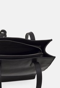 Černá kožená taška přes rameno s zipovým oddílem, dvěma pevným popruhy a jemnou podšívkou. Má strukturovaný design a minimalistický styl.