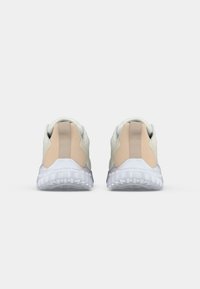 Adidași albi și bej cu o textură netedă, având o talpă transparentă, guler căptușit și un panou lateral elastic pentru suport.