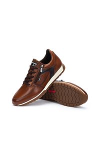 Sneakers in pelle marrone con design a lacci, cerniera laterale, dettagli neri e suola in gomma texture con un intersuola bianca.