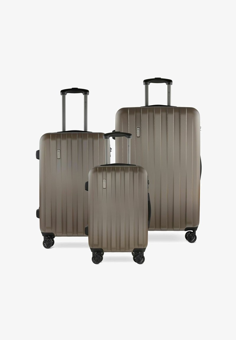 Trois valises rigides de couleur taupe métallique, présentant des rainures verticales, des poignées télescopiques et quatre roues noires pour une facilité de déplacement.