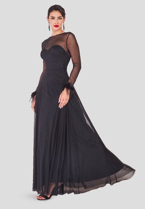 Robe noire longue jusqu'au sol avec un tissu transparent à pois, des manches longues, des accents en plumes aux poignets, et un corsage ajusté. Jupe fluide et lisse.