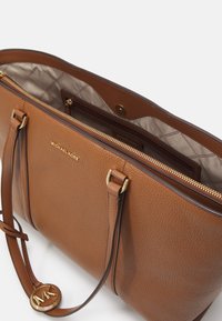 Borsa a tote in pelle marrone con finitura texture, accessori in tono oro e scomparto con zip. Presenta manici superiori doppi e una fodera interna.