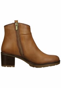 Bottine en cuir marron avec fermeture éclair latérale, bout arrondi et talon bloc empilé sur fond blanc.