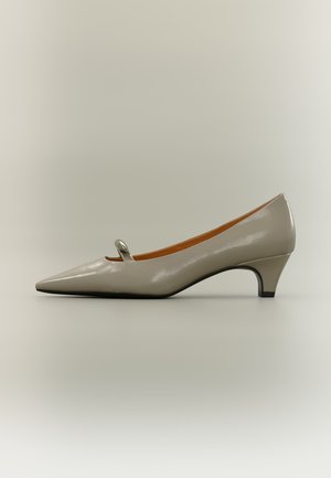Chaussure pour femme beige brillante à talon bas et bout pointu, avec une petite bride arrondie sur le dessus avant.