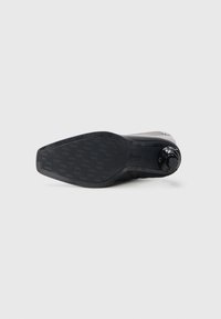 Black shoe sole with a textured surface and star pattern. Features a circular adjustment dial on the side for fit customization.