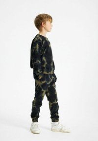 Zwart en olijf kleurige tie-dye sweatshirt en jogger set, gemaakt van katoen, relaxte pasvorm, elastische boorden, gestyled met witte sneakers.