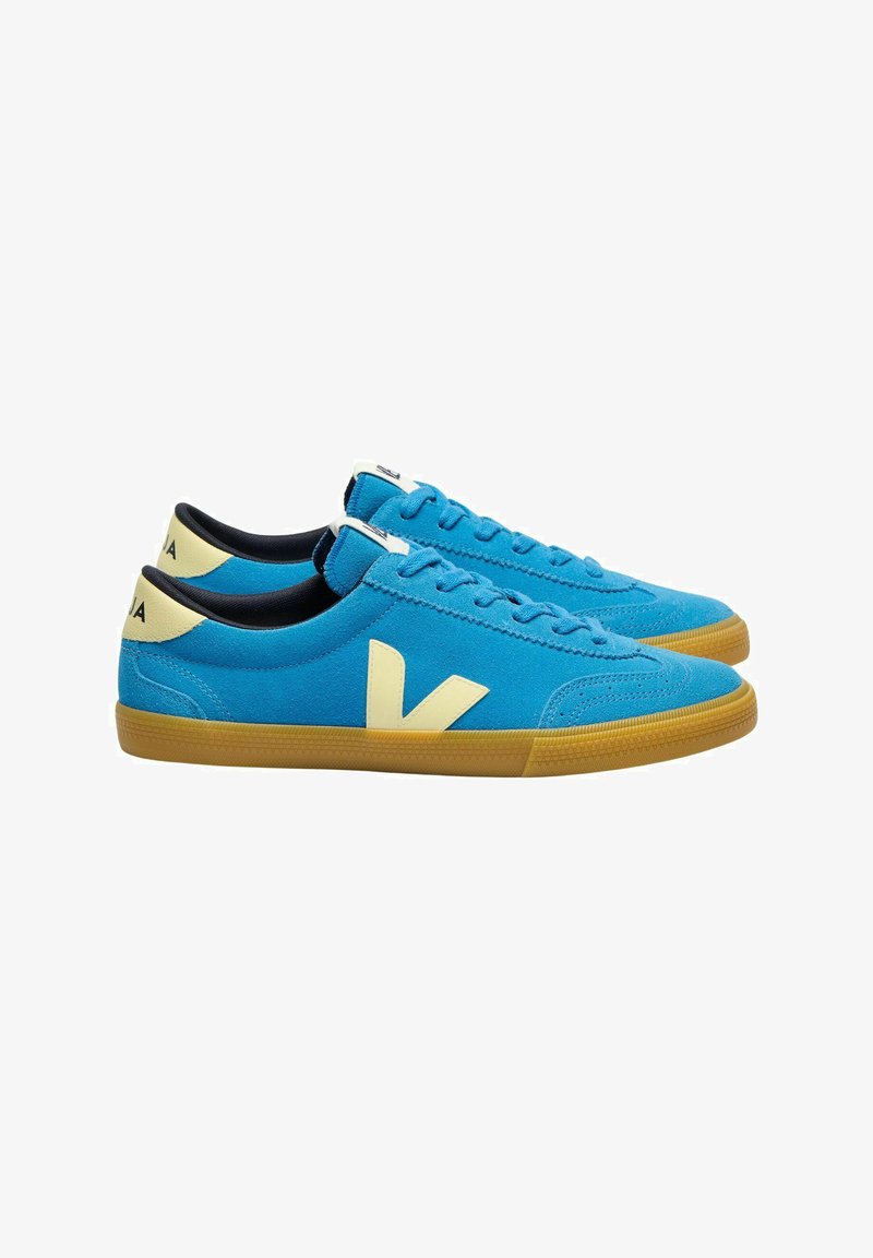 Blauwe suède sneakers met gele accenten, voorzien van een wit logo en een gumrubberen zool. Vetersluiting met een gestructureerd oppervlak.