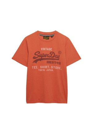 Orange kortærmet T-shirt med vintage SuperDry-logo, japansk tekst og "TEE. SHIRT. STORE. TOKYO, JAPAN." trykt på fronten.