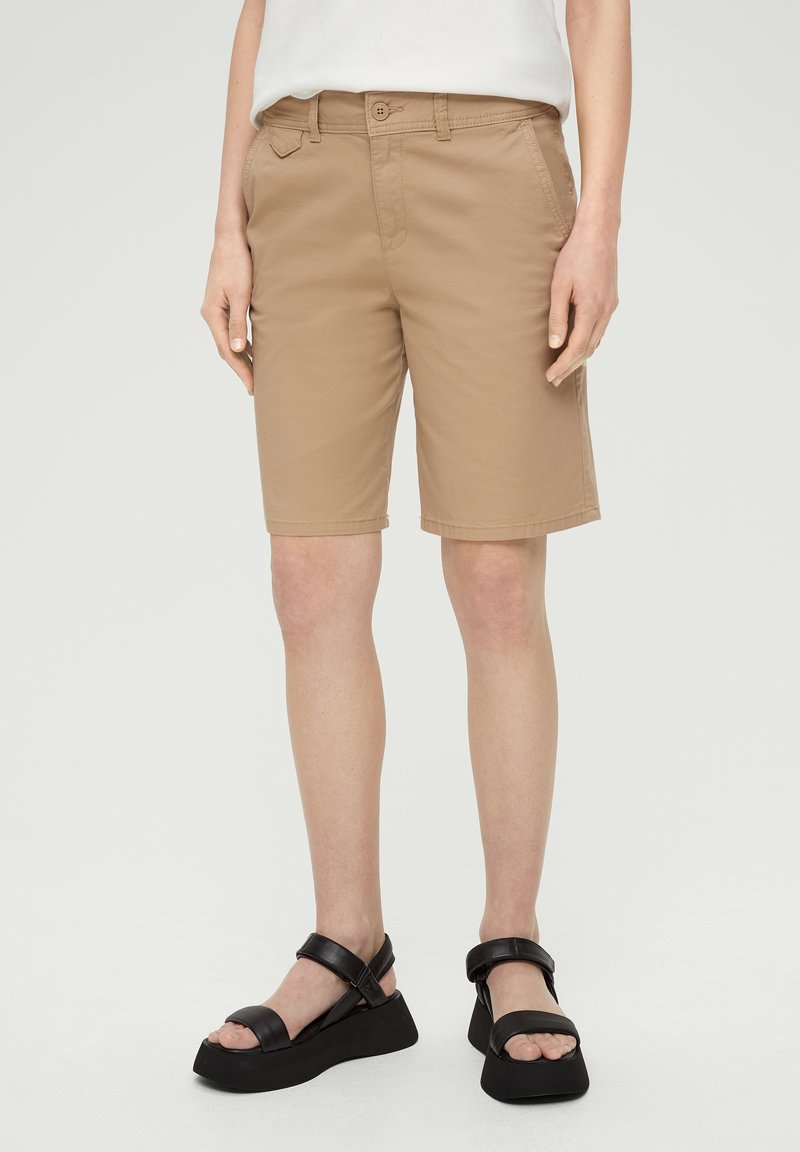 Beige, knielange shorts met een knoopsluiting, voorzakken en een gladde textuur, gecombineerd met zwarte plateausandalen.