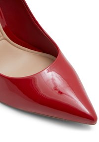 Escarpin en cuir verni rouge avec un bout pointu et une finition lisse et brillante. L'intérieur est nude avec un design minimaliste.