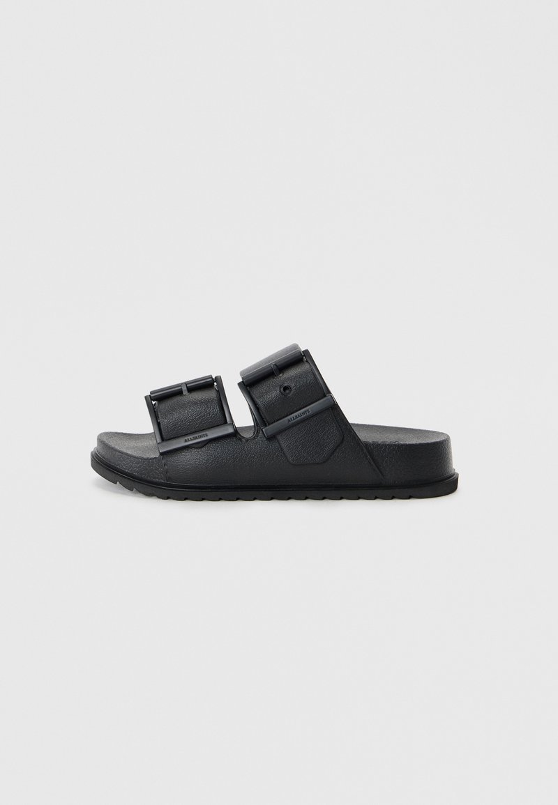 Schwarze Riemchensandalen aus strukturiertem Material mit zwei verstellbaren Riemen und Schnallen. Flacher Absatz mit einem gemusterten Profil für besseren Halt.