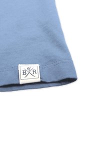 Blå bomulds T-shirt med korte ærmer og flad kant. Har et hvidt rektangulært mærke med "BR" og krydset design. Glat tekstur.