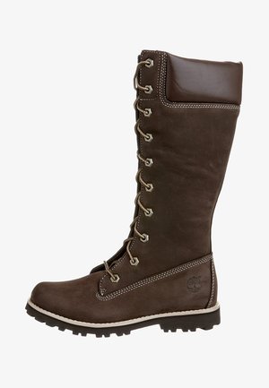 Bota alta hasta la rodilla de cuero marrón con parte superior lisa, cordones en la parte delantera, tobillo reforzado y suela robusta con tacos gruesos para tracción.