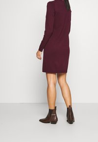 Burgundy långärmad klänning, rak skärning, knälång, kombinerad med texturerade bruna ankelstövlar, med en slät yta och låg klack.