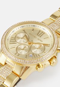 Orologio cronografo in oro con dettagli in cristallo, quadrante texturizzato e indicatori delle ore. Presenta un display della data e un bracciale in oro lucido.