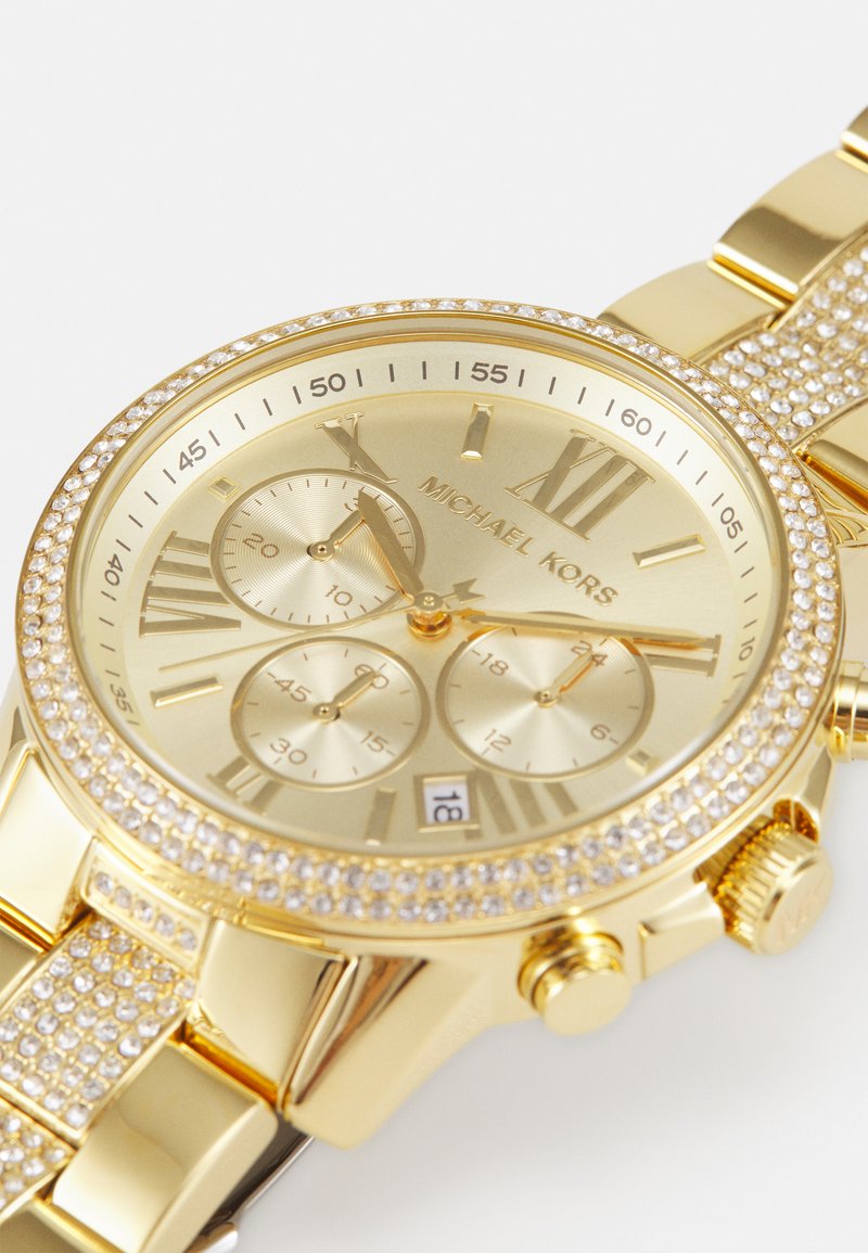 Goudkleurig chronograafhorloge met kristalaccenten, een gestructureerde wijzerplaat en uurmarkeringen. Beschikt over een datumaanduiding en een gepolijste gouden armband.