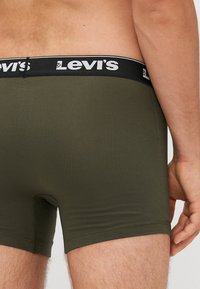 Boxer in verde oliva con elastico nero in vita con il logo "Levi's" bianco. Texture liscia, design aderente, senza pattern visibili.