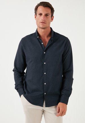 Camisa de manga larga azul oscuro con collar clásico, cierre de botones y textura suave, con botones blancos y un diseño ajustado.
