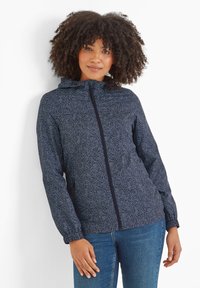 Navy hooded jacket with a white leaf pattern, zip closure, and elastic cuffs. Worn with blue jeans, featuring a relaxed fit and lightweight material.