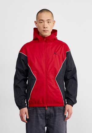 Red and black windbreaker jacket with a zip front, hood, elastic cuffs, and white accents. Features a small logo on the chest.
