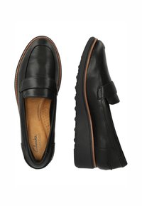 Svarta läderloafers med rund tå, accentuerade med bruna sömmar. Har en vadderad innersula och gummisula för komfort och hållbarhet.