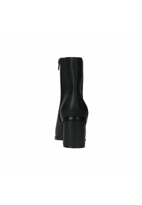 Bottines noires en matériau lisse, avec une fermeture éclair sur le côté, un embout arrondi et un talon épais. Design minimaliste sans accents visibles.