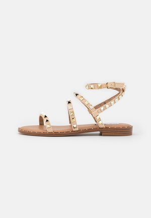 Sandalen met banden en een soepele bruine zool, voorzien van gouden studjes en een geweven bandontwerp in lichtbruin, vastgezet met een verstelbare gesp.