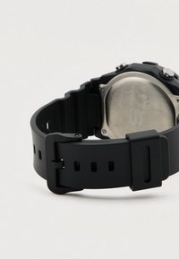 Čierne hodinky s textúrovaným gumovým remienkom, zadnou časťou z nehrdzavejúcej ocele a pevnou prackou. Remienok má niekoľko nastavovacích otvorov.