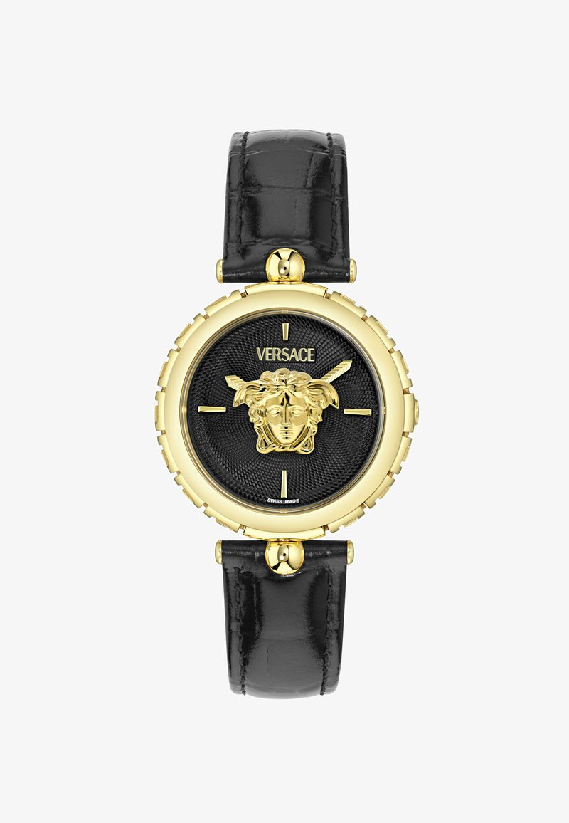 Kuldtooni kell ümara musta koonusketiga, millel on Medusa pea disain. Musta nahast rihm läikiva viimistlusega ja metallist detailide aktsentidega.
