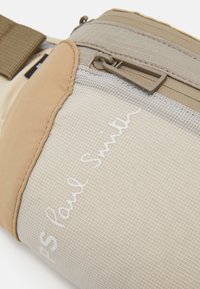 Beige stoffen pouch met een mesh paneel en een handgeschreven 'PS Paul Smith' detail. Voorzien van een grijze rits en een band voor een veilige sluiting en draaggemak.