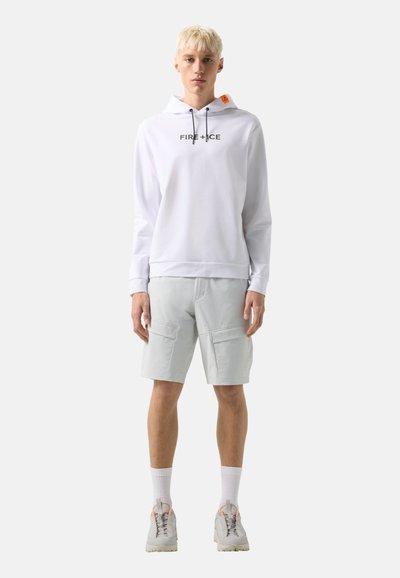 Young person with short blond hair wearing a white "FIRE+ICE" hoodie, light gray cargo shorts, white socks, and gray sneakers, standing facing forward.