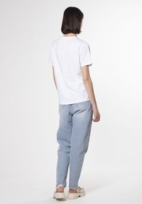 Hvid bomulds t-shirt med en simpel skæring, parret med lyseblå højtaljede jeans. Fodtøj med kraftige såler og stropper.