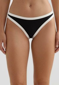 Czarne majtki od bikini z białym elastycznym paskiem w talii i wykończeniem, o niskim stanie i gładkiej fakturze materiału. Bez wzorów i metalowych elementów.