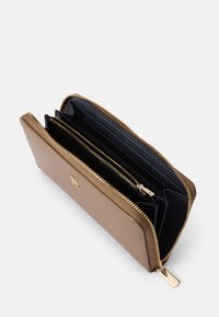 Braunes Lederportemonnaie mit goldenem Reißverschluss und Akzenten. Verfügt über ein marineblaues Innenfutter mit mehreren Fächern und Kartensteckplätzen zur besseren Organisation.