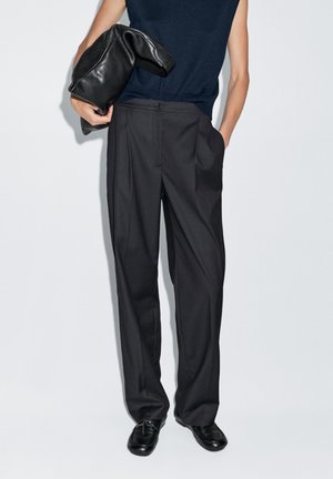Dark gray wide-leg trousers with a flat front, side pockets, and a smooth texture, paired with a black leather bag and a navy top.